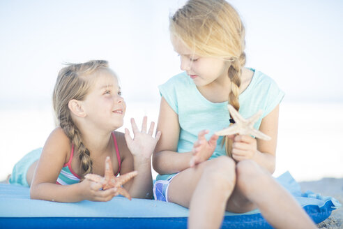 Zwei Mädchen am Strand auf einer Luftmatratze mit Seesternen - ZEF003354