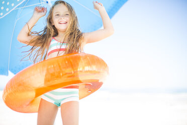 Happy girl on beach with orange floating tyre - ZEF003361