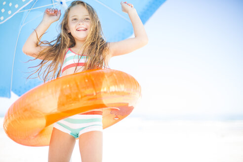 Glückliches Mädchen am Strand mit orangefarbenem Schwimmreifen - ZEF003361