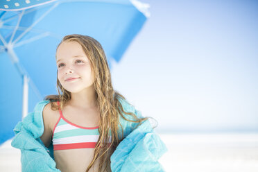 Smiling girl on beach drying off with a beach towel - ZEF003362