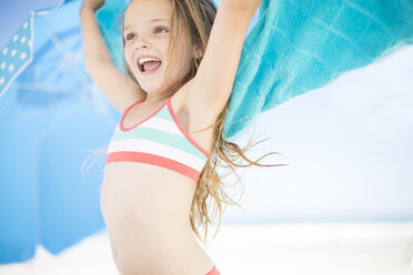 Lächelndes Mädchen am Strand, das sich mit einem Strandtuch abtrocknet - ZEF003368