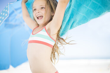 Smiling girl on beach drying off with a beach towel - ZEF003368