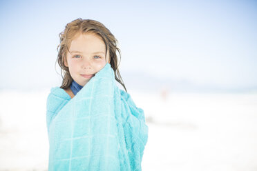 Lächelndes Mädchen am Strand, eingewickelt in ein Handtuch - ZEF003369