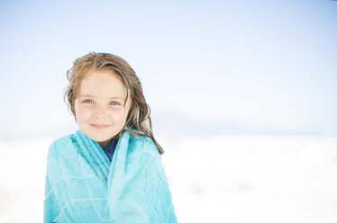 Lächelndes Mädchen am Strand, eingewickelt in ein Handtuch - ZEF003370