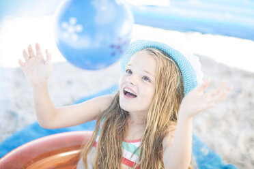 Smiling girl on beach playing with a ball - ZEF003375