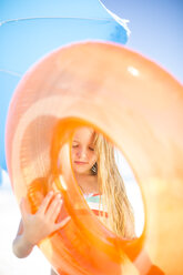 Mädchen am Strand hält einen orangefarbenen Schwimmreifen - ZEF003377
