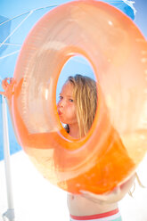Girl on beach inflating an orange floating tyre - ZEF003378
