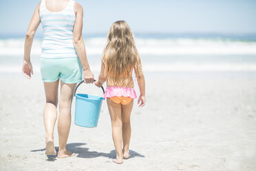 Mutter und Tochter am Strand, die mit einem Eimer spazieren gehen - ZEF003380