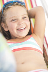 Happy girl on beach relaxing on a beach chair - ZEF003389