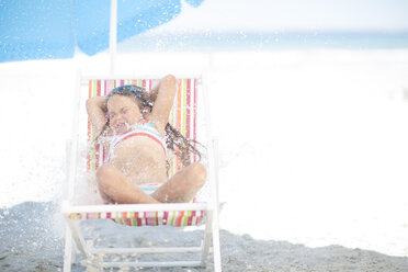 Mädchen am Strand auf einem Liegestuhl liegend wird mit Wasser bespritzt - ZEF003391