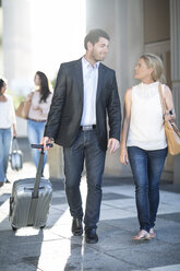 Businessman pulling suitcase walking next to woman - ZEF003266