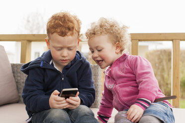 Little boy and girl looking at cell phone - NNF000301