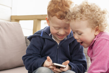 Kleiner Junge und Mädchen schauen auf ihr Handy - NNF000303