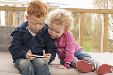 Kleiner Junge und Mädchen schauen auf ihr Handy - NNF000357