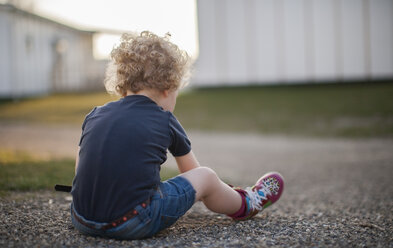 Little girl sitting on gravel path - NNF000323