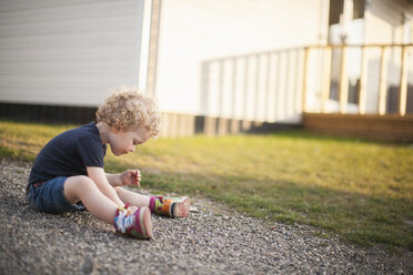 Little girl sitting on gravel path - NNF000324