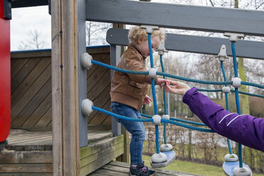 Mutter hilft ihrer kleinen Tochter beim Gehen auf dem Spielplatz - NNF000328