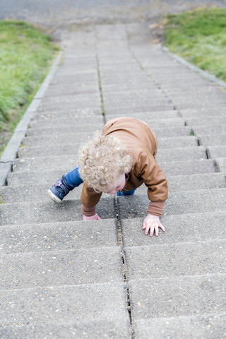 Kleines Mädchen krabbelt die Treppe hoch, lizenzfreies Stockfoto