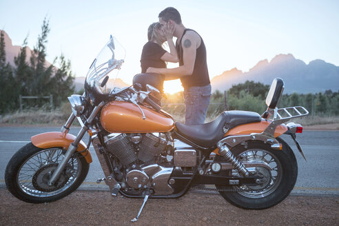 Küssendes Paar neben einem Motorrad am Straßenrand - ZEF003584