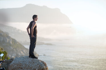 South Africa, Cape Town, motorcyclist standing on rock at the coast enjoying view - ZEF003605