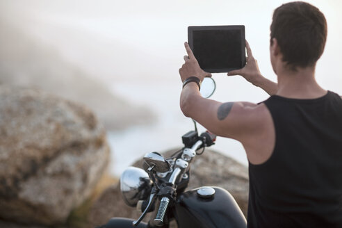 Südafrika, Kapstadt, Motorradfahrer an der Küste beim Fotografieren mit digitalem Tablet - ZEF003610
