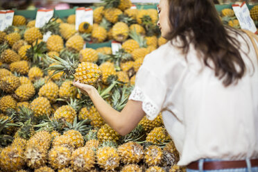 Frau prüft Ananas an einem Obststand - ZEF004185