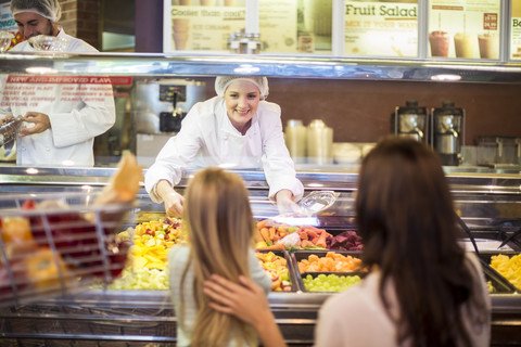 Mother and daughter buying fruit salad in supermarket stock photo