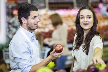 Shop assistant helping customers choosing fruits - ZEF004204