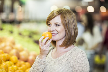 Junge Frau im Supermarkt hält Orange - ZEF004207