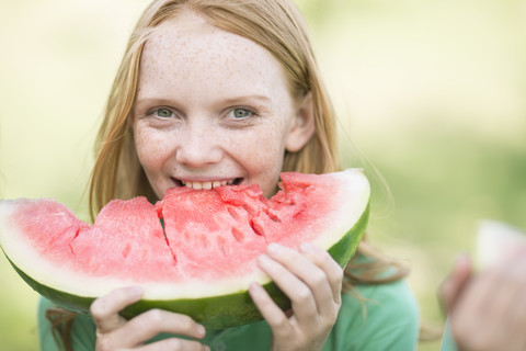 Porträt eines Mädchens mit roten Haaren, das eine Scheibe Wassermelone isst, lizenzfreies Stockfoto