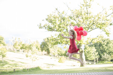 Mädchen mit roten Luftballons im roten Kleid springt in die Luft - ZEF004389
