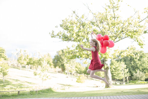 Mädchen mit roten Luftballons im roten Kleid springt in die Luft - ZEF004389