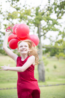Portrait of running girl with red balloons wearing red dress - ZEF004391