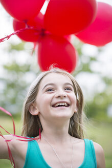 Porträt eines lächelnden Mädchens mit roten Luftballons - ZEF004393