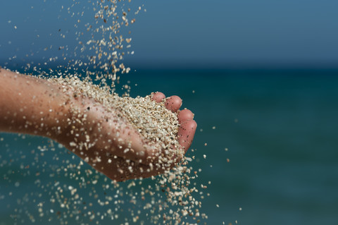 Hand eines Kindes, das am Strand mit Sand spielt, lizenzfreies Stockfoto