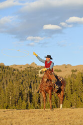 USA, Wyoming, Cowboy auf seinem Pferd sitzend, der sein Lasso wirft - RUEF001397