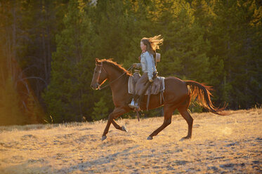 USA, Wyoming, riding cowgirl at backlight - RUEF001401