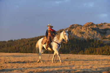 USA, Wyoming, junger Cowboy reitet im Abendlicht - RUEF001405