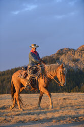 USA, Wyoming, Cowgirl reitet im Abendlicht - RUEF001407