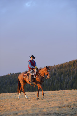 USA, Wyoming, Cowboyreiten im Abendlicht, lizenzfreies Stockfoto