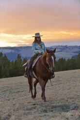 USA, Wyoming, Cowgirl reitet im Abendlicht - RUEF001412