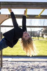 Girl hanging head first on playground equipment - MGOF000012