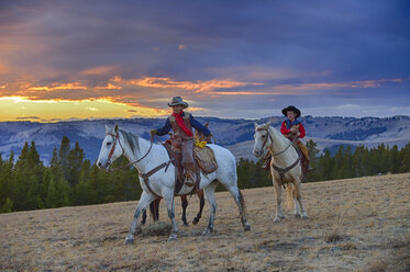 USA, Wyoming, zwei junge Cowboys reiten bei Sonnenuntergang durch die Wildnis - RUEF001414