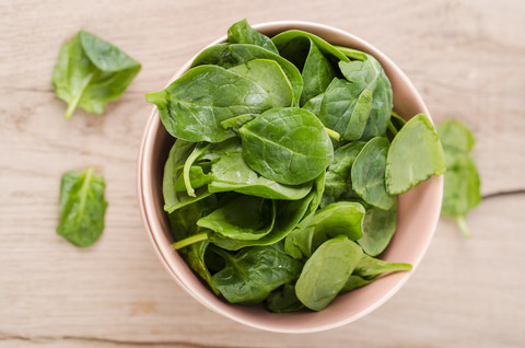 Bowl of fresh spinach leaves on wood stock photo