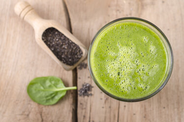 Glass of spinach smoothie, shovel of chia seeds and spinach leaf on wood - ODF001012