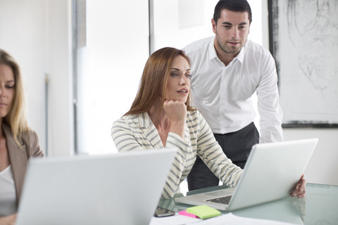 Geschäftsfrauen und Geschäftsmann im Büro arbeiten an Laptops, lizenzfreies Stockfoto