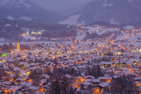 Deutschland, Bayern, Blick auf das schneebedeckte, beleuchtete Oberstdorf in der Dämmerung vor den Allgäuer Alpen - WG000560
