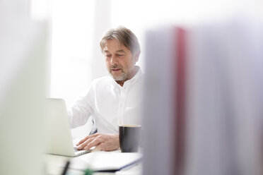 Businessman using laptop at desk - WESTF020493