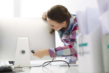 Junge Frau im Büro, die einen Computerbildschirm anschließt - WESTF020500