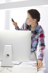 Junge Frau im Büro, die einen Computerbildschirm anschließt - WESTF020501